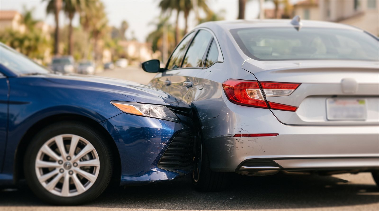 Minor rear-end car accident between two sedans on a sunny Southern California street